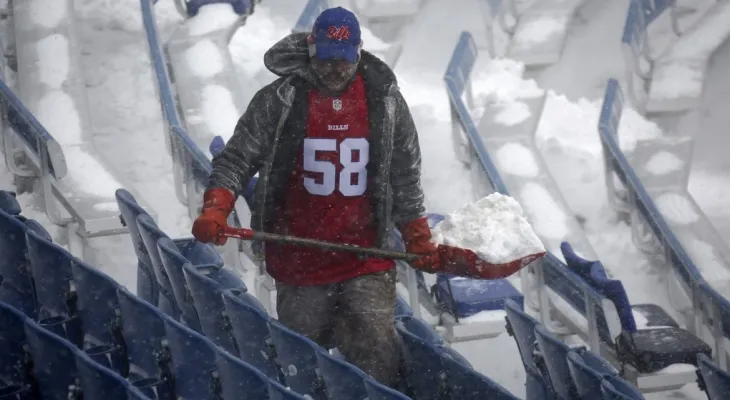 Volunteers contribute to cleaning the snow-covered field for a playoff game of the Buffalo Bills team